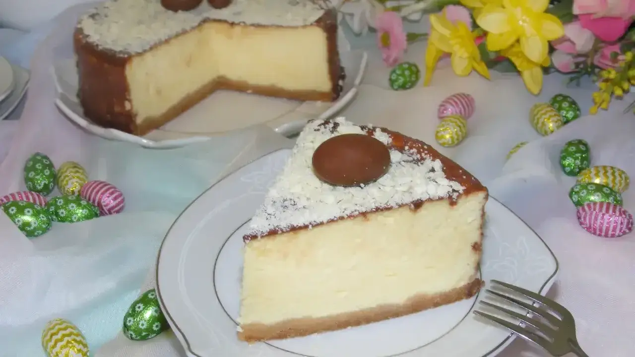 Pyszny sernik z mascarpone, udekorowany czekoladowymi jajeczkami i wiórkami białej czekolady, na wielkanocnym stole.