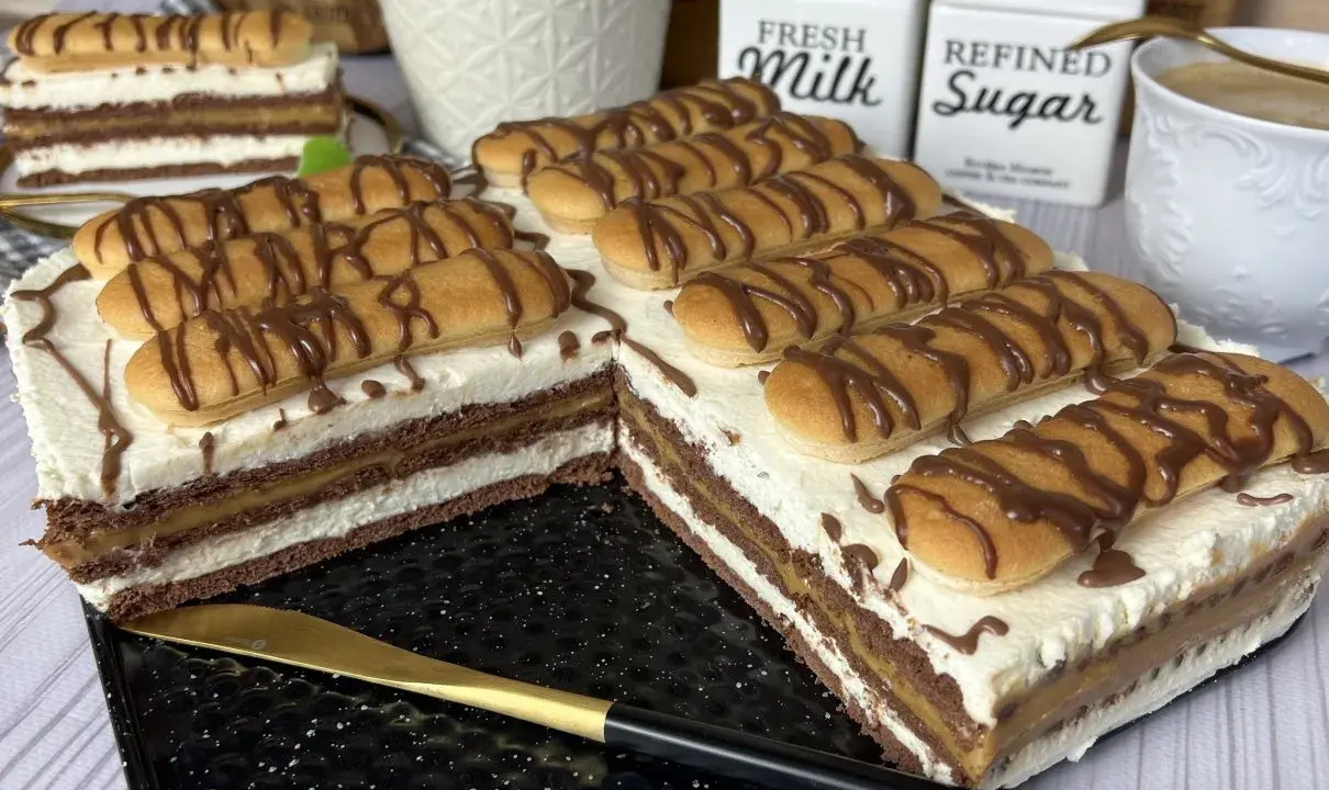 Pyszne ciasto z kajmakiem, przełożone kremem i biszkoptami, polane czekoladą. Idealne na deser!