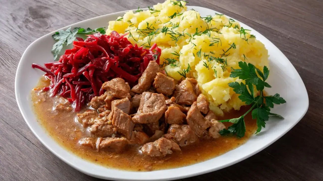 Pyszny gulasz z łopatki wieprzowej z ziemniakami i buraczkami, udekorowany natką pietruszki i koperkiem.