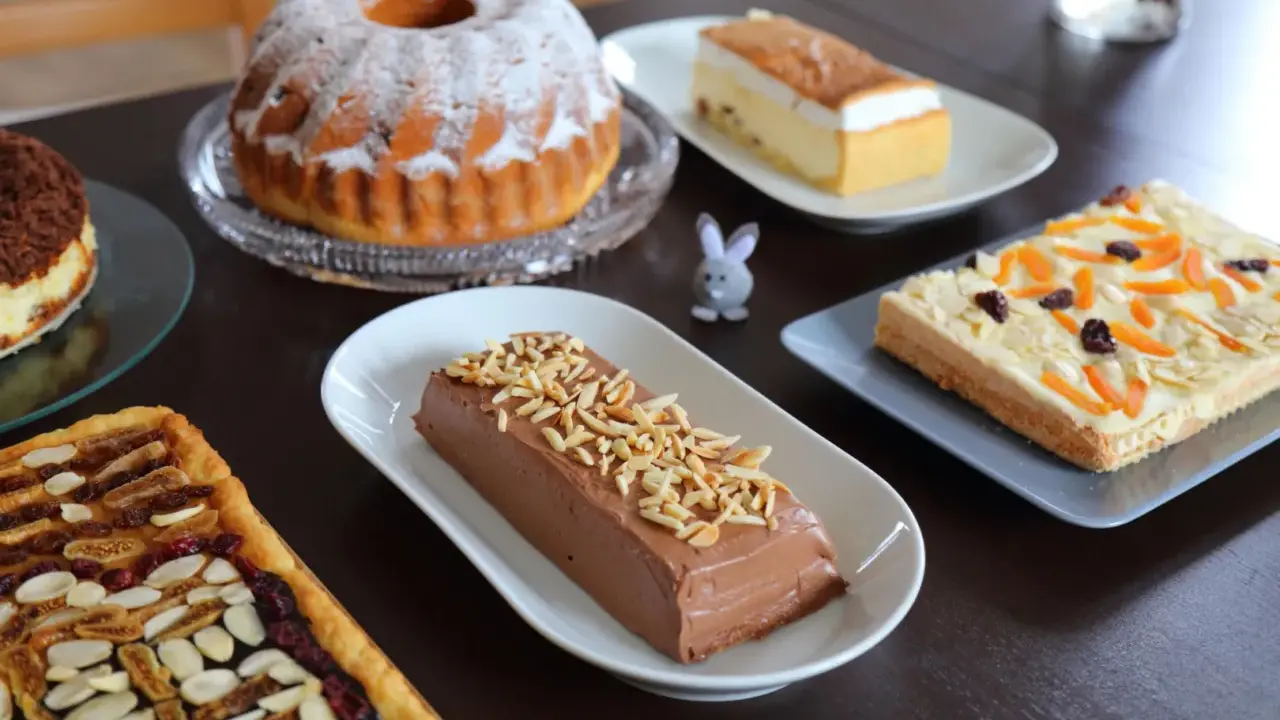 Wielkanocne ciasto na stole: babka, sernik, czekoladowy deser i tartaletka z bakaliami.