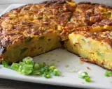 Pyszna tortilla de patatas, pokrojona na kawałki, z zieloną cebulką na talerzu.