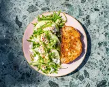 Orzeźwiająca sałatka z melonem, serem feta, ogórkiem i rukolą, posypana płatkami chili. Obok tost z przyprawami.