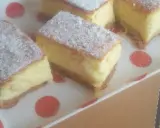 Kawałki puszystego ciasta z kremowym nadzieniem, posypane cukrem pudrem. To zaskakujący sernik bez sera, który zachwyca smakiem.