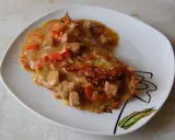 Pyszny placek po cygańsku z gulaszem mięsnym i papryką, podany na białym talerzu z ozdobnym wzorem.