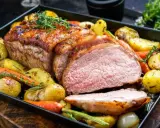 Soczysta polędwiczka wieprzowa z piekarnika, pieczona z ziemniakami i marchewką, ozdobiona ziołami.
