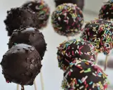Czekoladowe cake pops na patyczkach, niektóre posypane kolorową posypką. Idealne na imprezę, łatwy cake pops przepis.