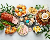 Wielkanocny stół pełen pyszności: pieczona szynka, babki, jajka, ciasto i słodkości.
