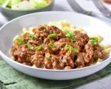 Pyszny przepis na strogonowa z wieprzowiny z pieczarkami i ogórkiem kiszonym, podany z makaronem.