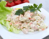 Pyszna sałatka z surimi, ziemniaków i warzyw, udekorowana natką pietruszki i liściem sałaty.