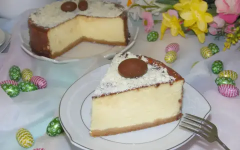 Pyszny sernik z mascarpone, udekorowany czekoladowymi jajeczkami i wiórkami białej czekolady, na wielkanocnym stole.