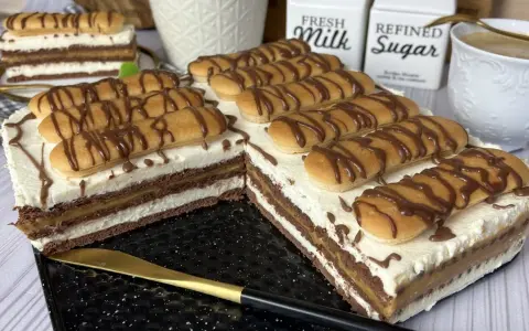 Pyszne ciasto z kajmakiem, przełożone kremem i biszkoptami, polane czekoladą. Idealne na deser!