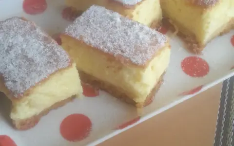 Kawałki puszystego ciasta z kremowym nadzieniem, posypane cukrem pudrem. To zaskakujący sernik bez sera, który zachwyca smakiem.