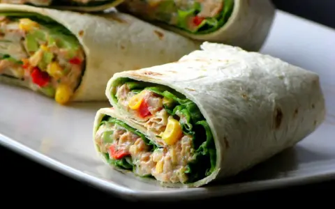 Pyszna tortilla z tuńczykiem, chrupiącą sałatą, kukurydzą i papryką. Idealna na szybki lunch.