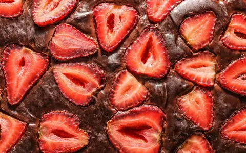 Pyszny brownie z truskawkami, z kawałkami owoców zatopionymi w czekoladowym cieście.