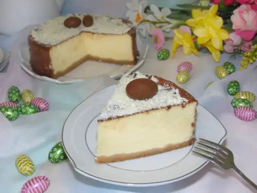 Pyszny sernik z mascarpone, udekorowany czekoladowymi jajeczkami i wiórkami białej czekolady, na wielkanocnym stole.