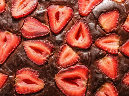Pyszny brownie z truskawkami, z kawałkami owoców zatopionymi w czekoladowym cieście.