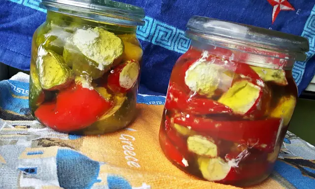 Dwa słoiki marynowanych papryczek nadziewanych serem feta na zimę. Papryczki w zalewie z oliwy i przypraw.