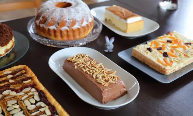 Wielkanocne ciasto na stole: babka, sernik, czekoladowy deser i tartaletka z bakaliami.