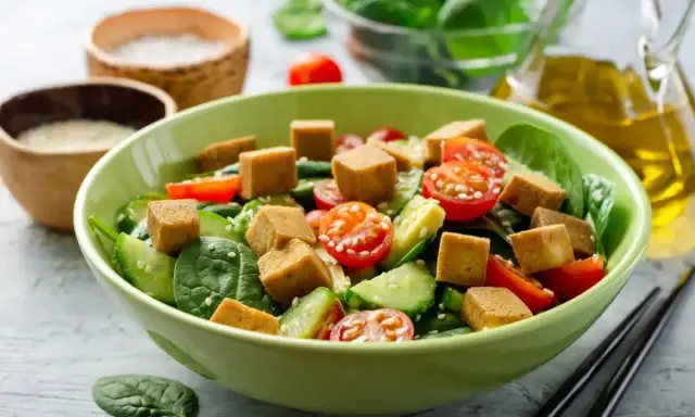 Pyszna sałatka z tofu, pomidorkami koktajlowymi i ogórkiem, posypana sezamem. Idealna na lekki posiłek.