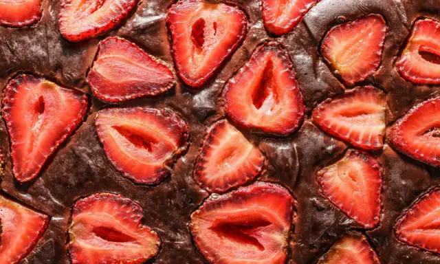 Pyszny brownie z truskawkami, z kawałkami owoców zatopionymi w czekoladowym cieście.