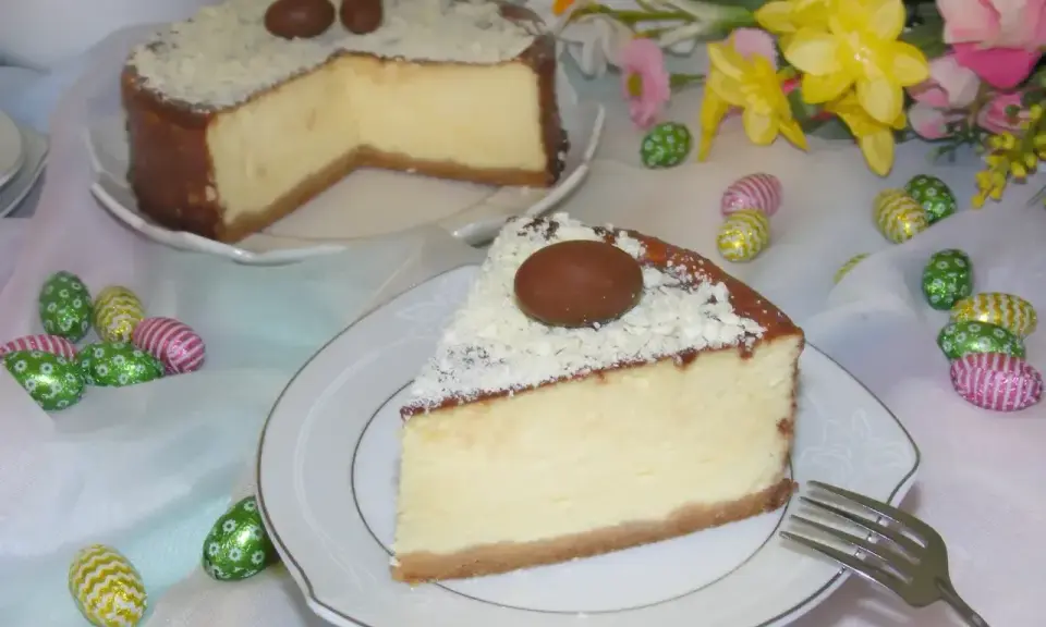 Pyszny sernik z mascarpone, udekorowany czekoladowymi jajeczkami i wiórkami białej czekolady, na wielkanocnym stole.