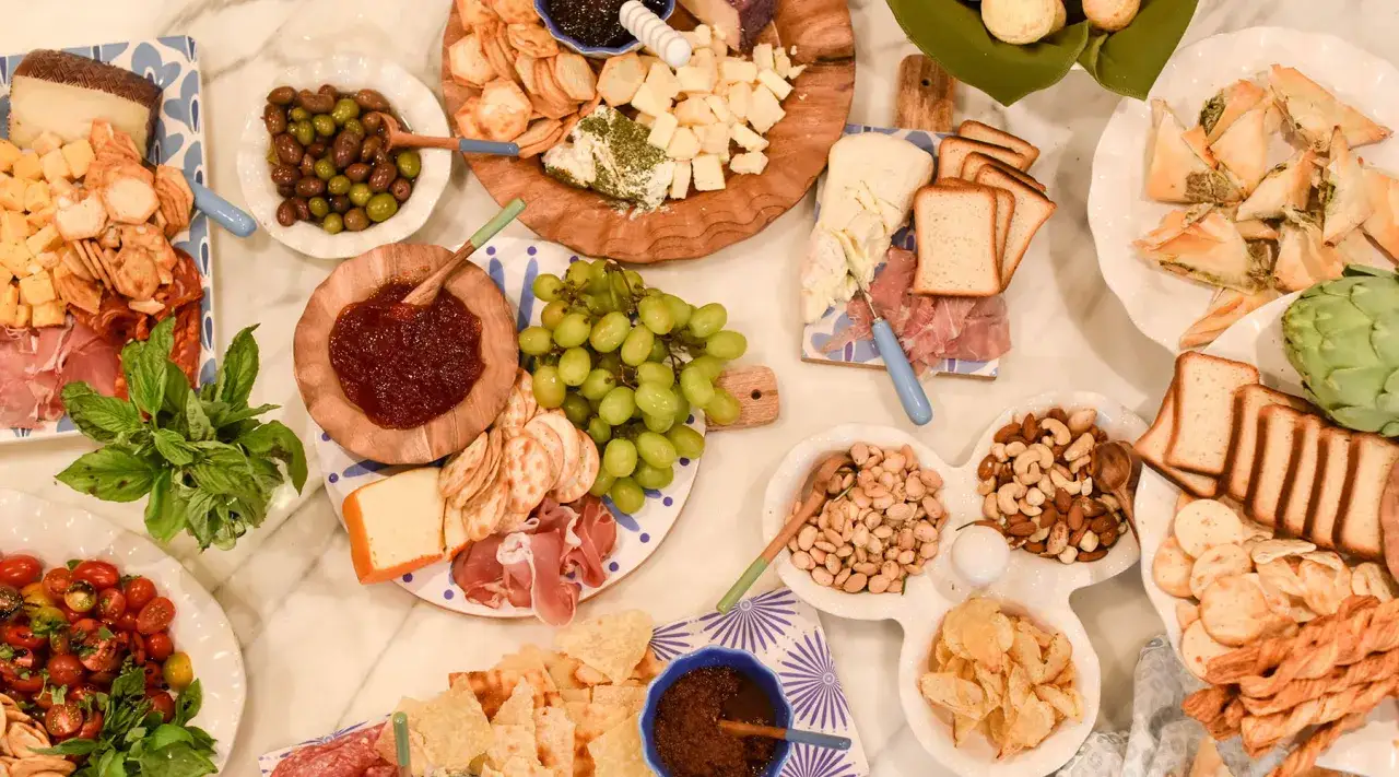 Idealne mini przekąski na imprezę: sery, oliwki, winogrona, pieczywo, chipsy i inne smakołyki.