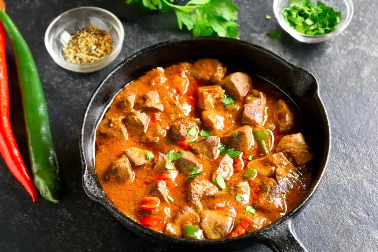 Gulasz Ani Gotuje w żeliwnej patelni, z papryczkami chili i ziołami. Pyszne danie gotowe do podania.