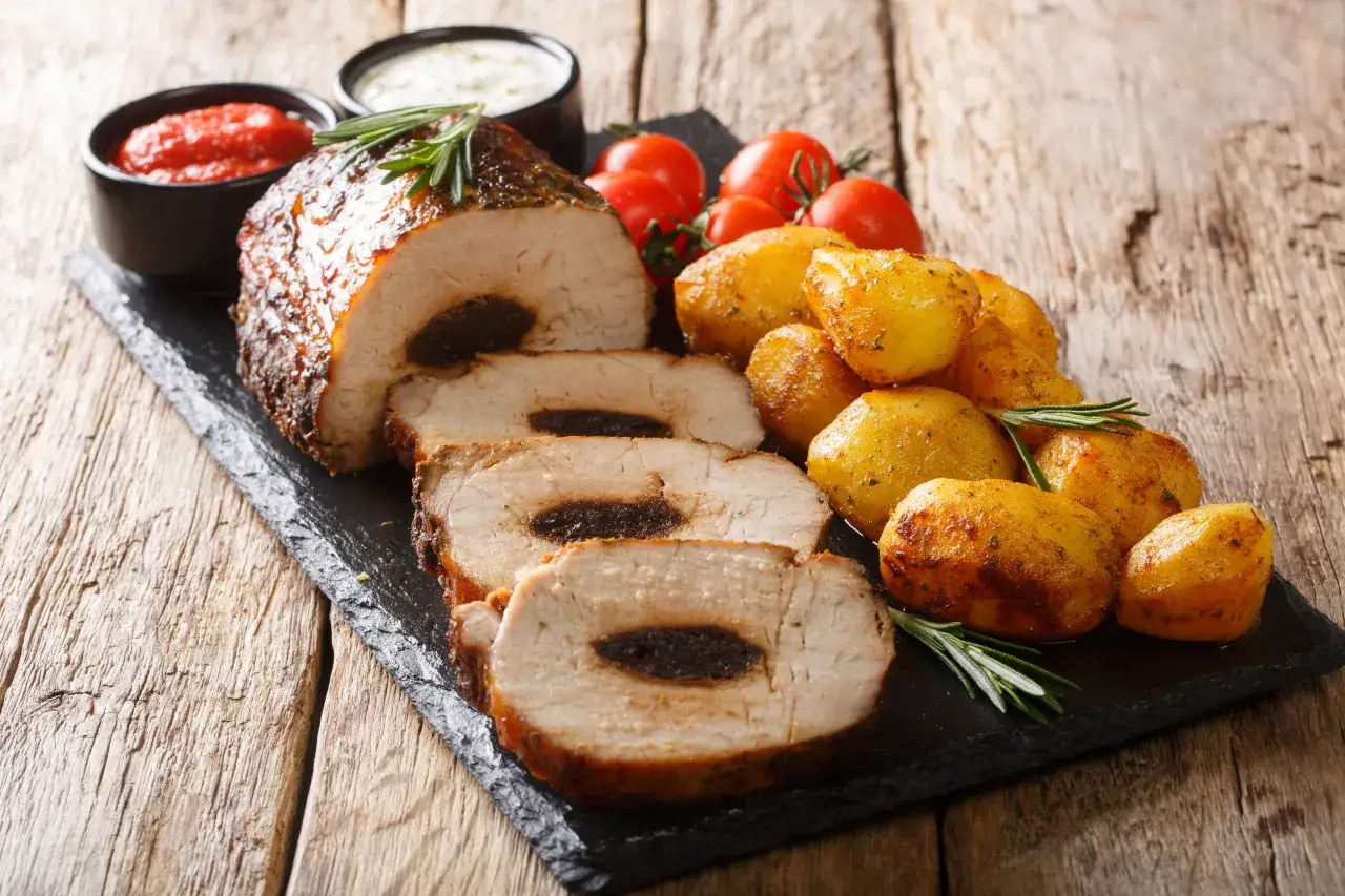 Pyszny schab faszerowany śliwkami, pieczone ziemniaczki, pomidorki i sosy. Idealny pomysł, co zrobić ze schabu na obiad.